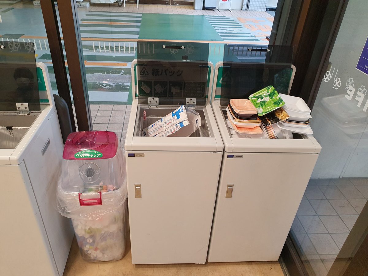 A source-segregation recycling station in Japan with separate bins for paper cartons, PET bottle caps, and styrofoam food trays