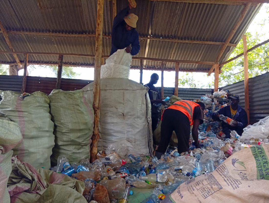 RevoWaste collectors sorting and baling plastic bottles at a recovery facility
